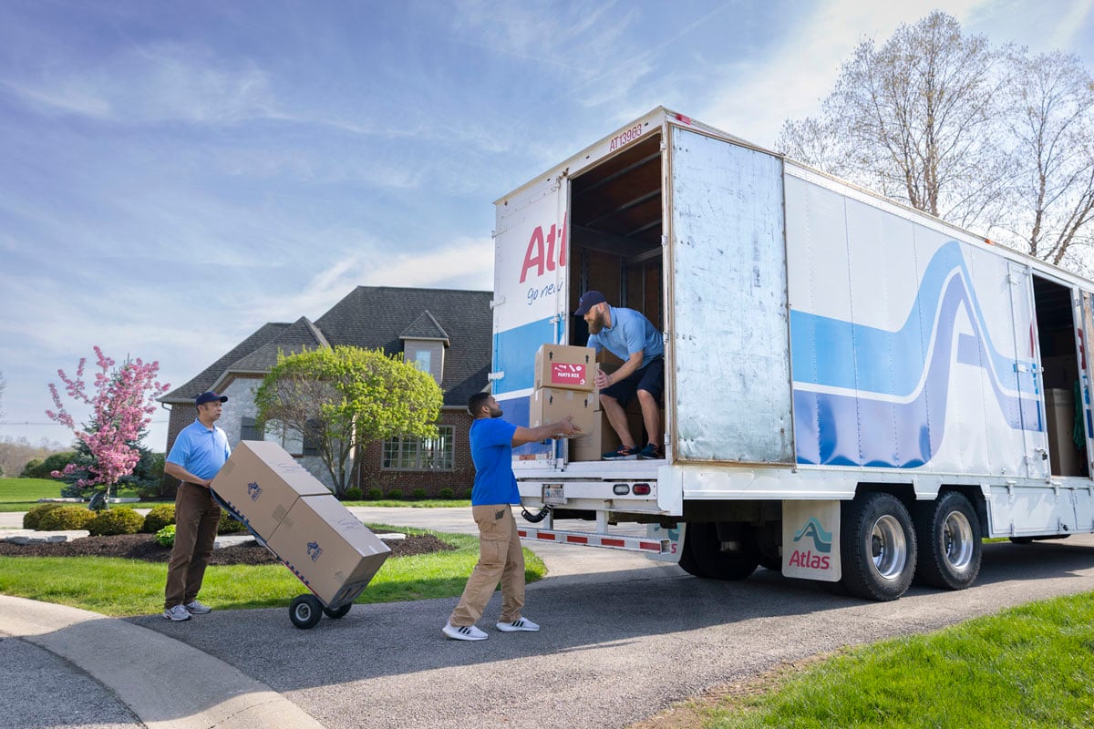 Atlas team members carefully packing household items with protective supplies inside a home interior.