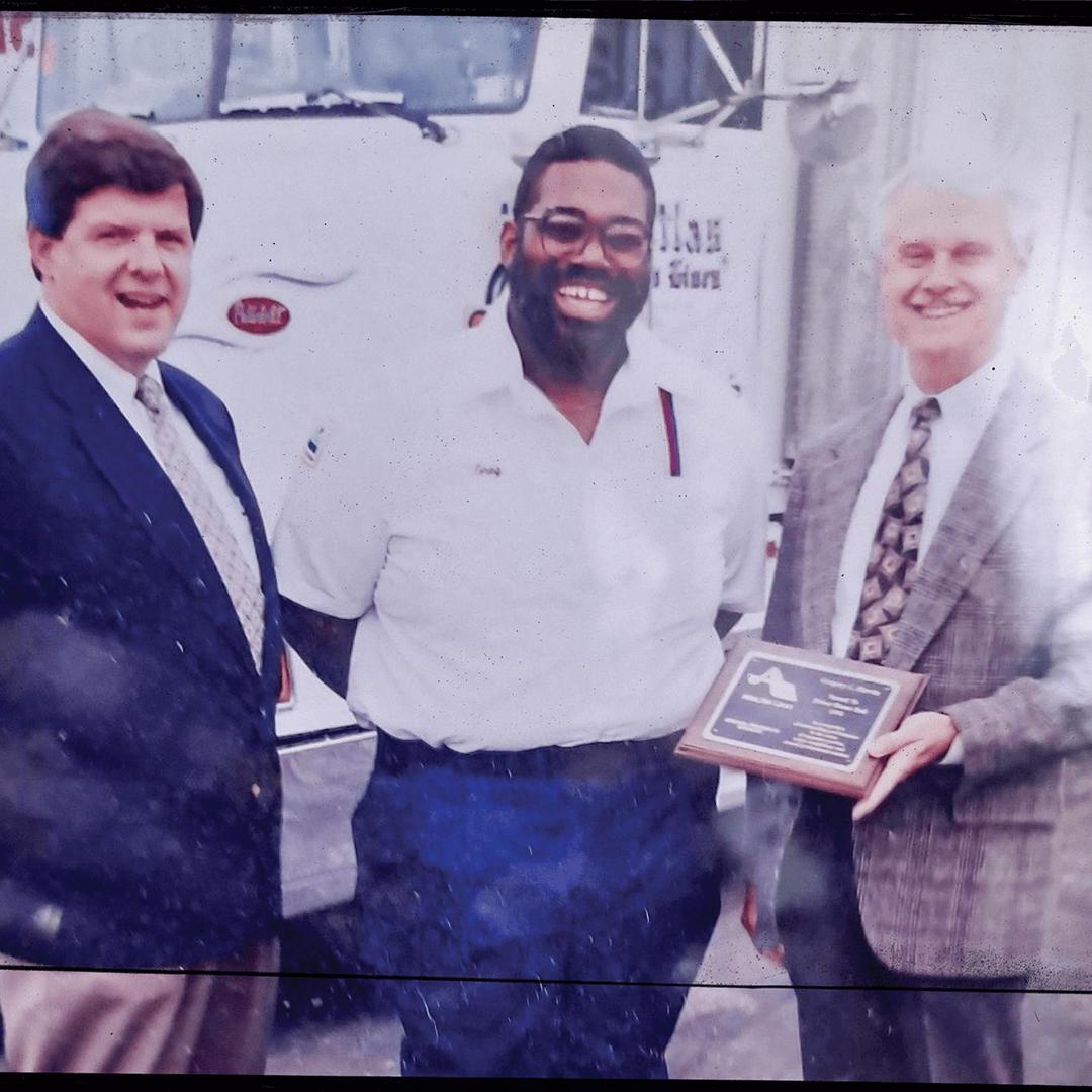 Greg Harvin smiles as he receives an award in front of a moving truck